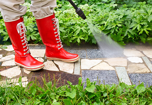 Person in galoshes power washing a walkway